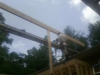 Carpenter setting a ridge beam over a new addition frame — Ice Dam Removal by Roofing Brothers in Morganza