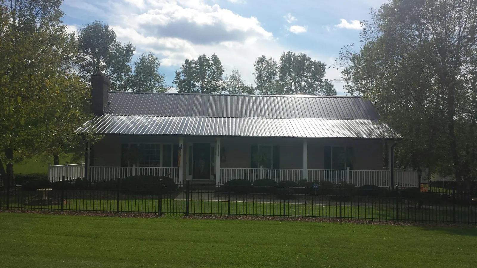 Gray metal roof on a brick ranch with a full width front porch — Gutter Guard Installation work by our crew in Morganza