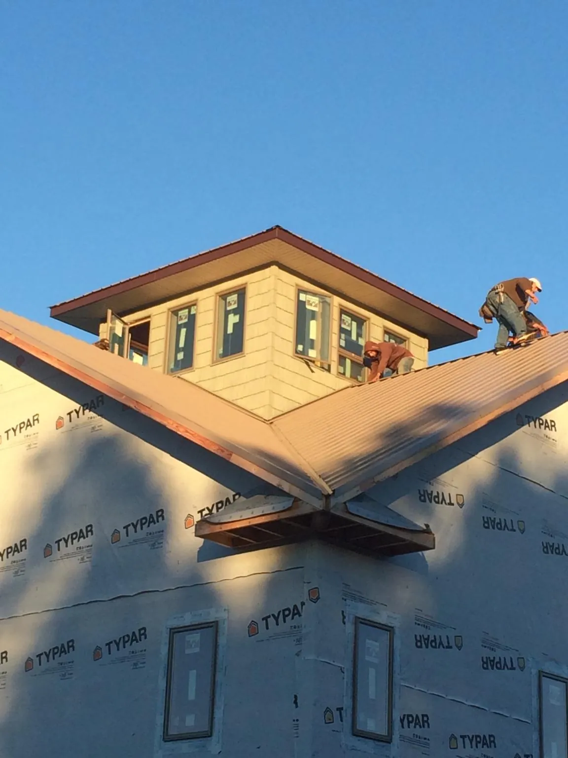 Roofers working around a rooftop cupola on a new metal roof at sunset — Roof Waterproofing in Morganza by Roofing Brothers